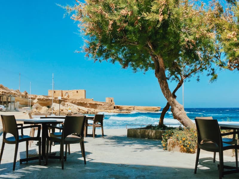 Photograph of a table and chairs in the foreground with the sea in the background.